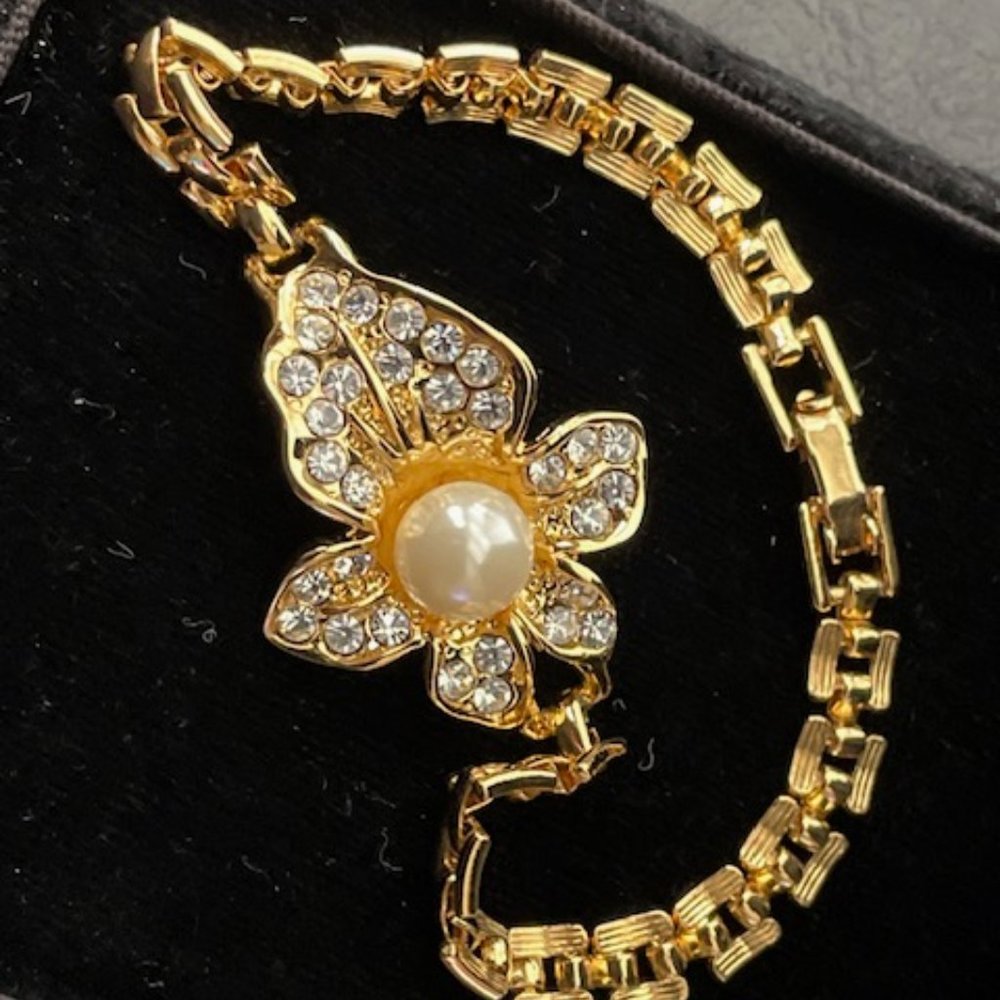 Gold metal tone bracelet with faux pearl and clear rhinestones flower